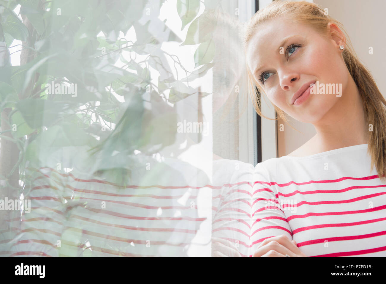Donna in piedi da una finestra Foto Stock