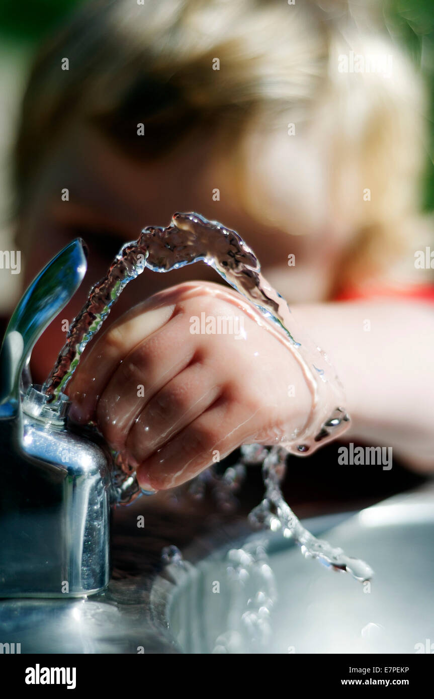 Un giovane ragazzo (2 1/2 anni) giocando con una fontana di acqua Foto Stock