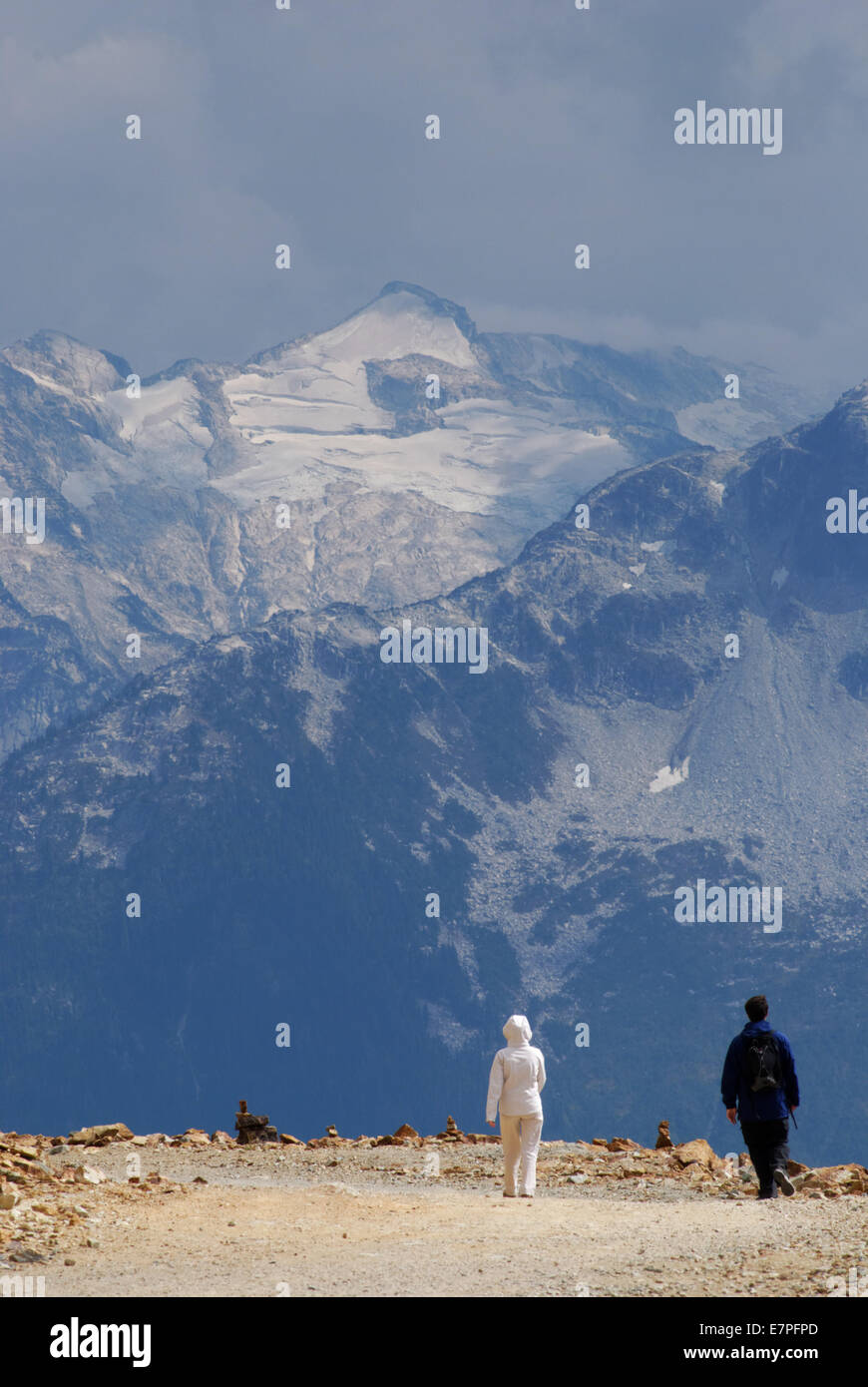Due turisti ammirando la luce drammatica e le vette delle montagne rocciose a Whistler, British Columbia, Canada Foto Stock