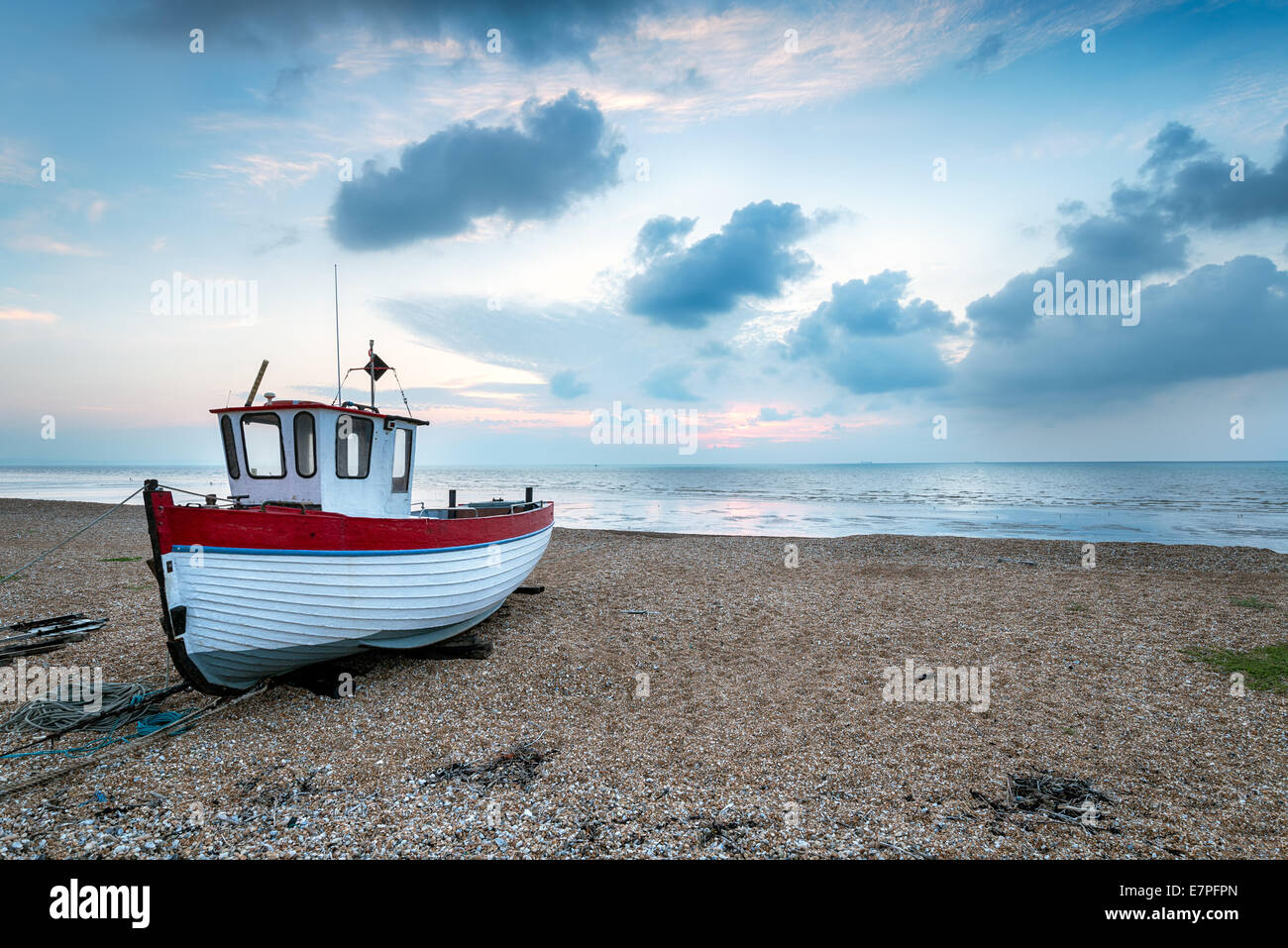 Una piccola barca sulla spiaggia al tramonto Foto Stock