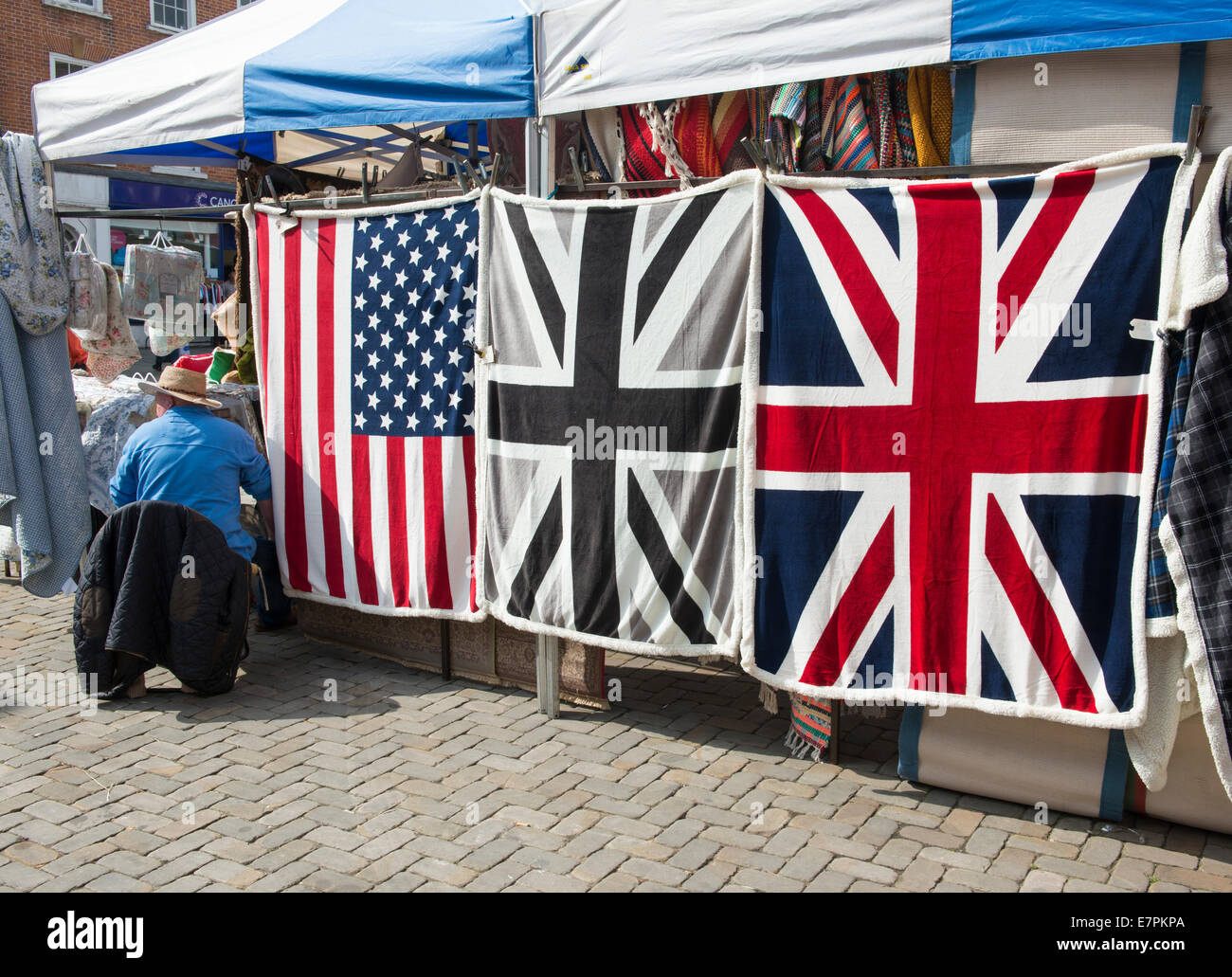 Plaid e coperte con UK e USA le bandiere in vendita su un mercato di Ludlow, Shropshire, Inghilterra Foto Stock