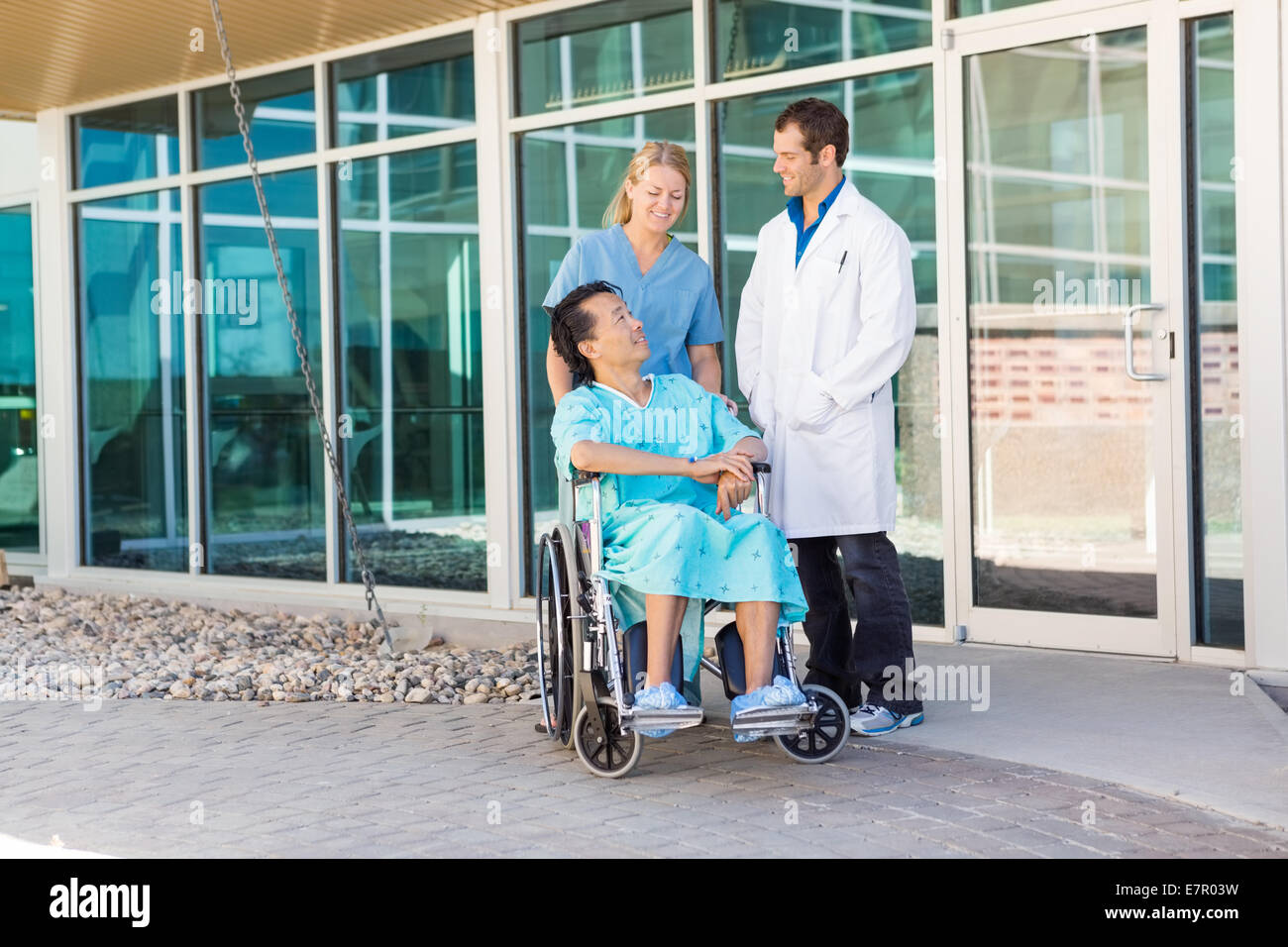 Infermiera e medico guardando il paziente su sedia a rotelle hospit al di fuori Foto Stock
