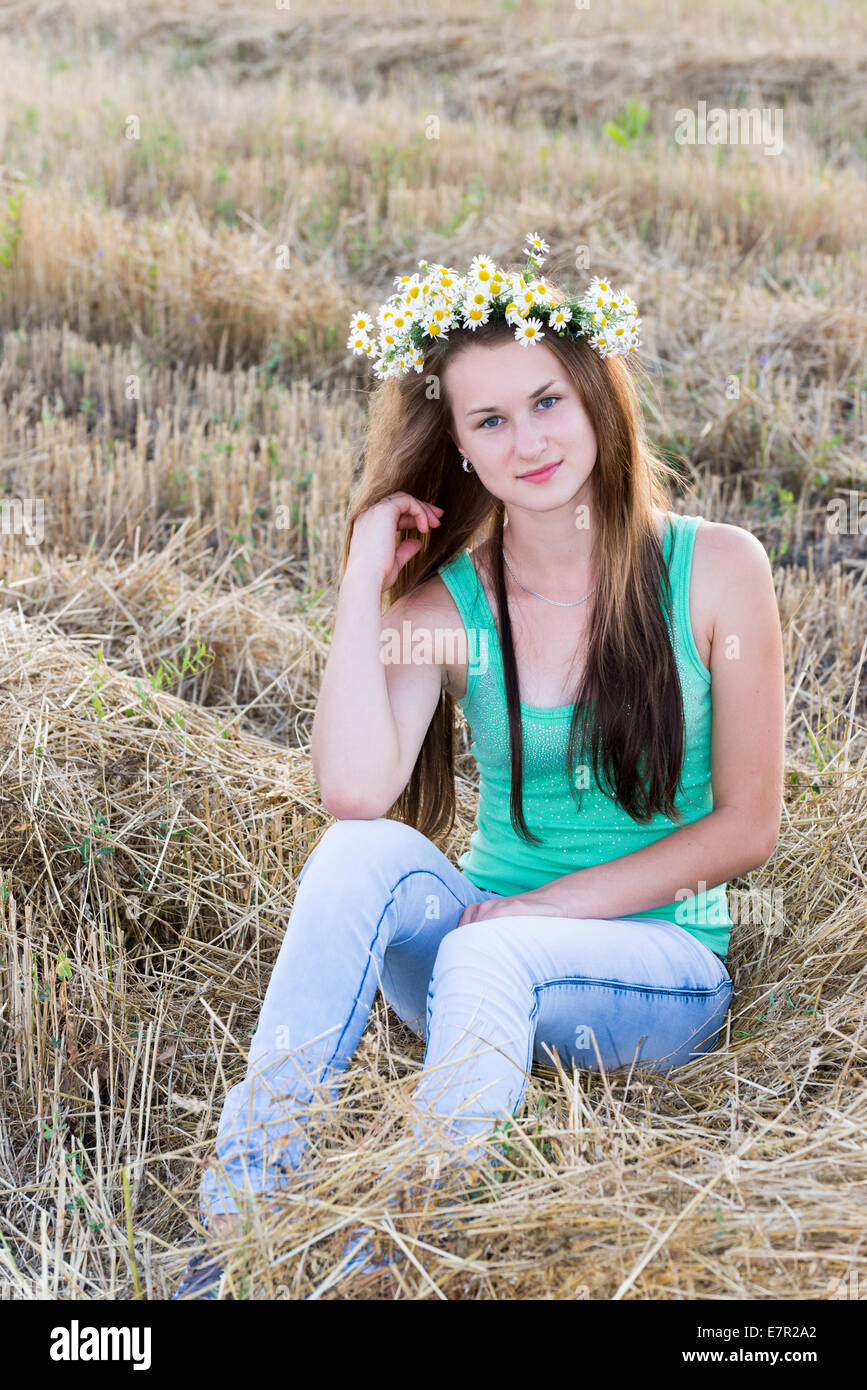 Teen ragazza con una ghirlanda di margherite nel campo Foto Stock