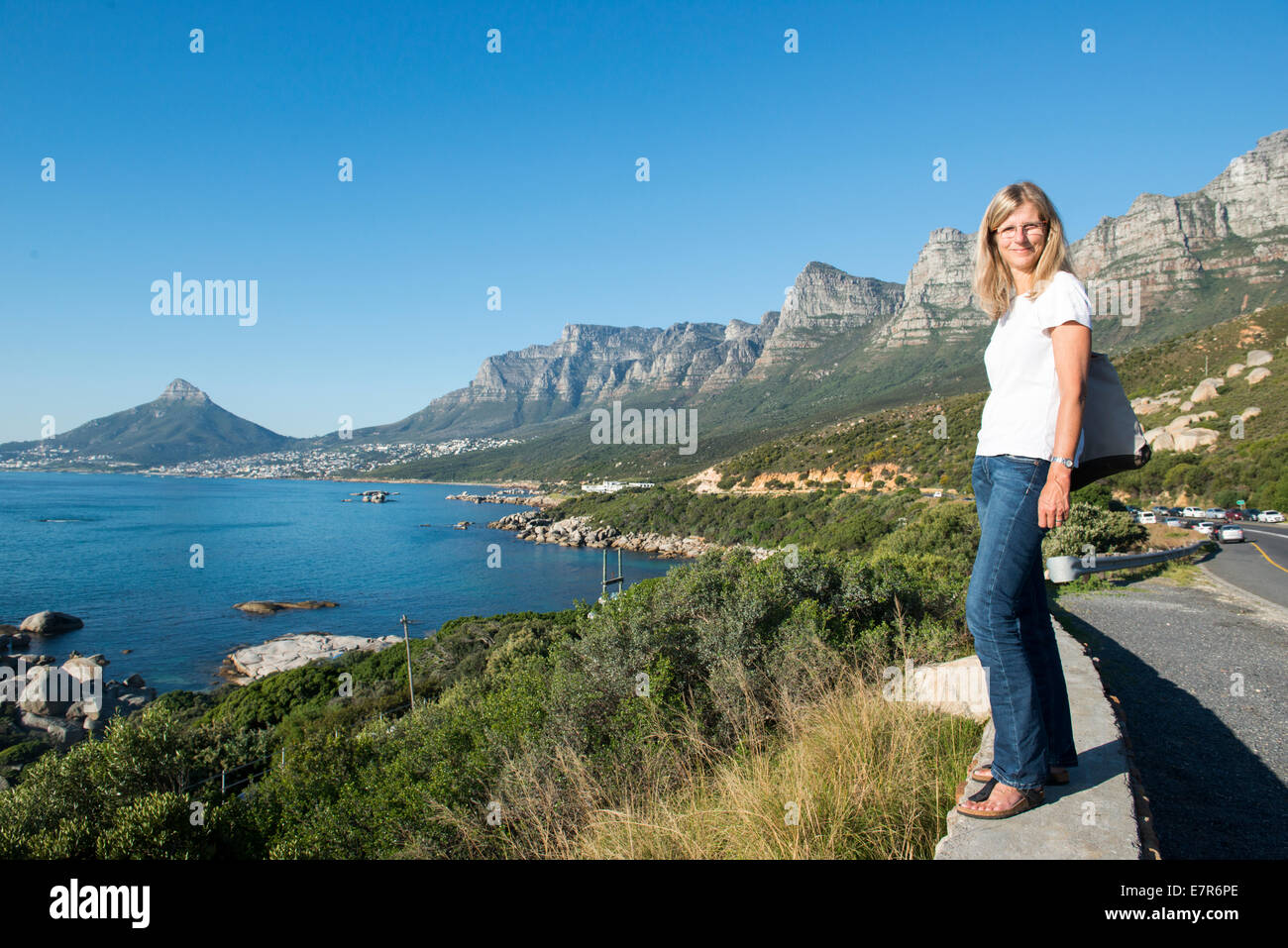 Turista femminile in piedi lungo la strada costiera che si affaccia sull'oceano a sud di Camps Bay, Città del Capo, Sud Africa Foto Stock