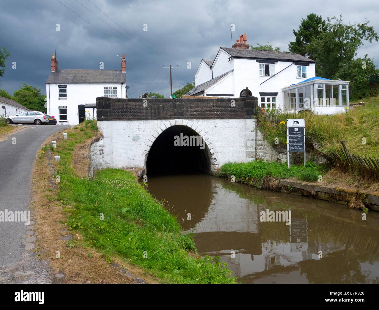 Il tunnel del canale per le chiatte con nuvole temporalesche e case superiore Foto Stock