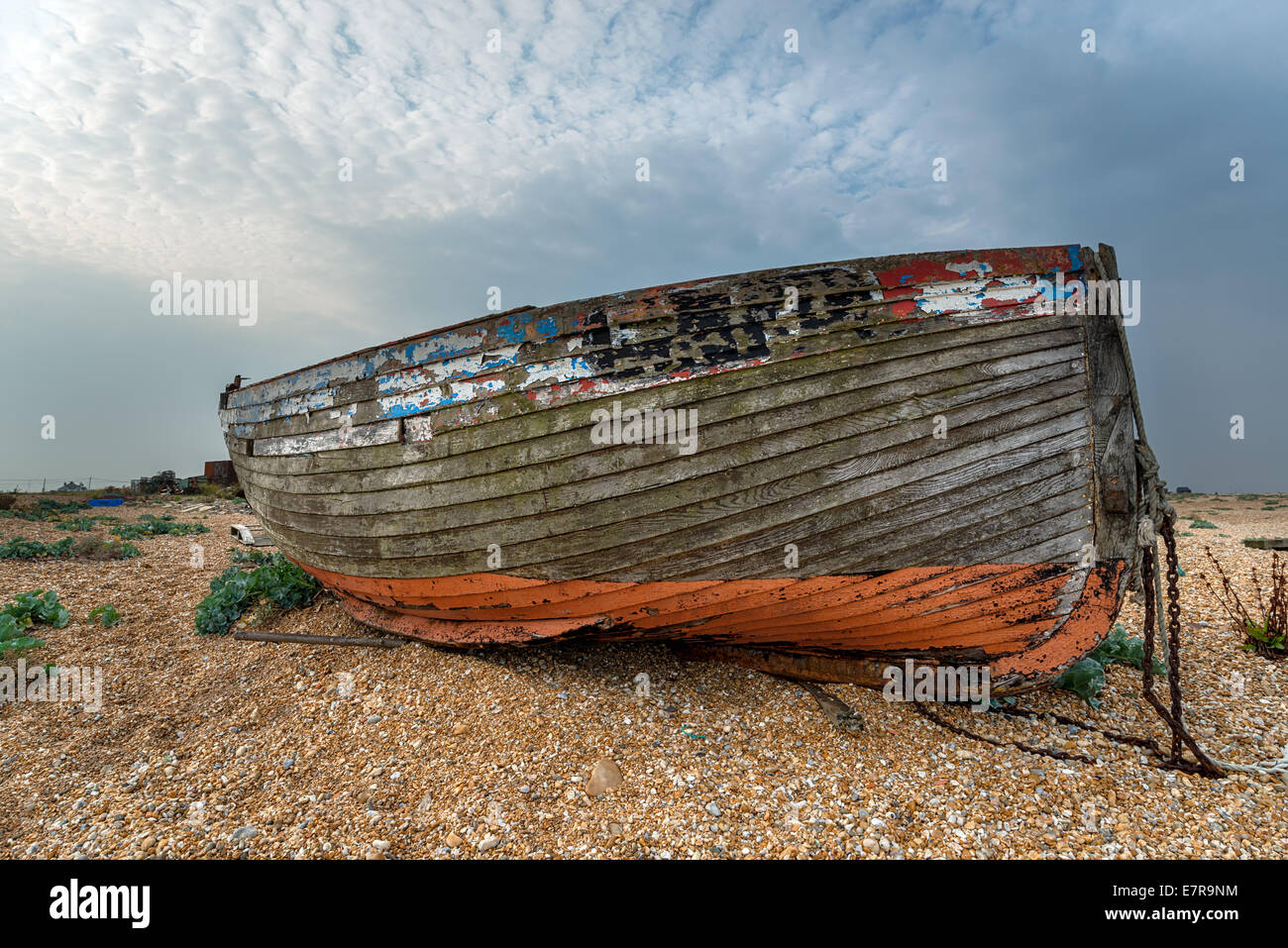 Un vecchio abbandonato naufragare in legno barca da pesca in alto su una spiaggia ghiaiosa Foto Stock