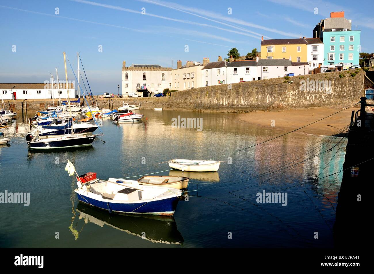 Barche locali nel vecchio porto di Tenby, Galles, con case colorate dietro le mura del porto Foto Stock