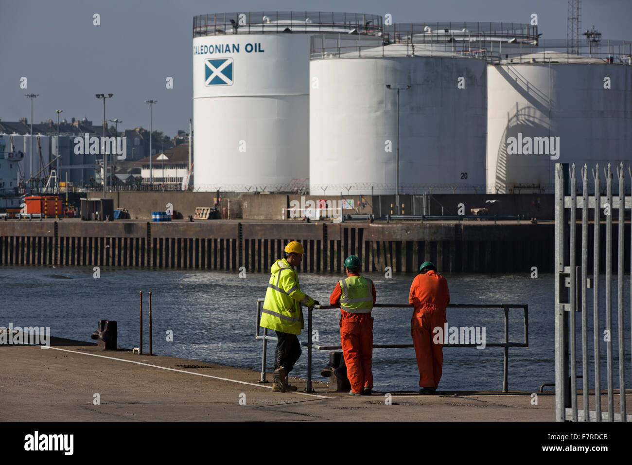 Il lavoro di tre uomini stavano in piedi su una banchina al porto di Aberdeen, Scozia il petrolio del Mare del Nord e del trasporto di gas hub. Foto Stock