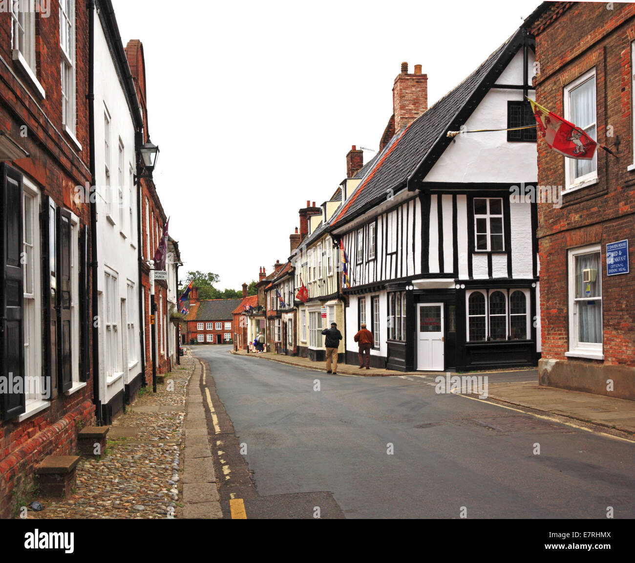 Una vista della High Street con il vecchio a metà degli edifici con travi di legno a Little Walsingham, Norfolk, Inghilterra, Regno Unito. Foto Stock