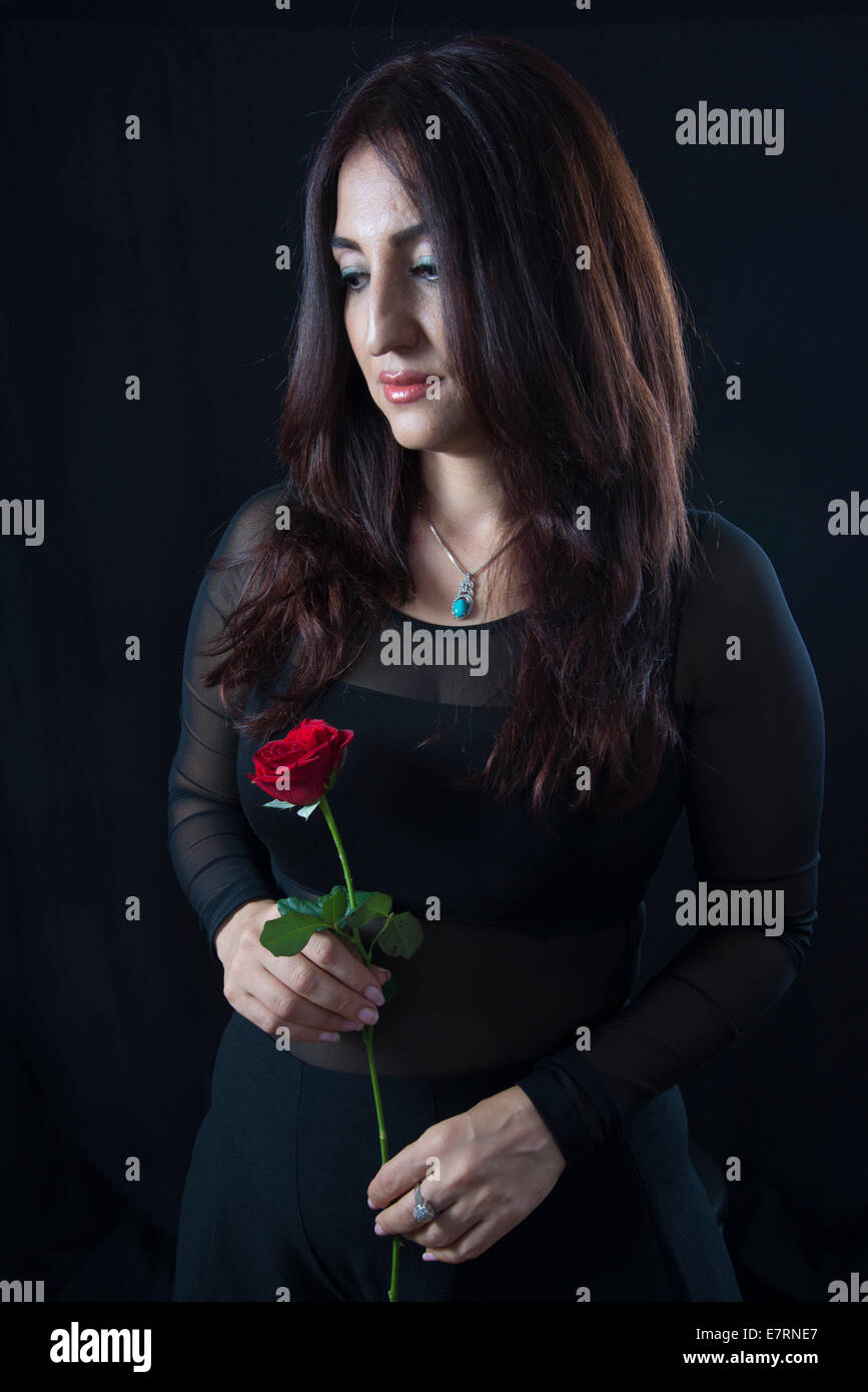 Bella bruna donna tenendo una rosa rossa Foto Stock