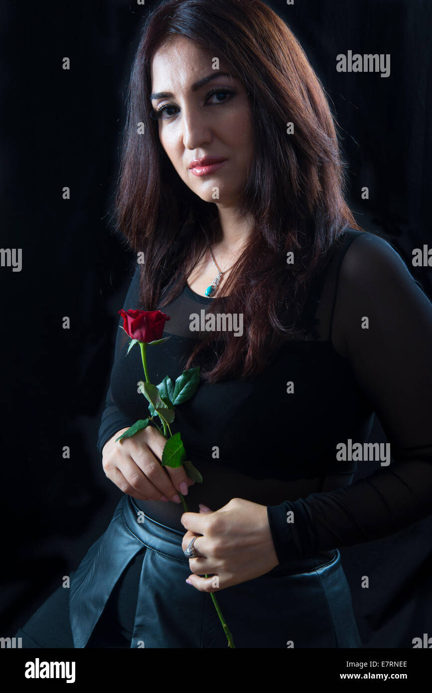 Bella bruna donna tenendo una rosa rossa Foto Stock