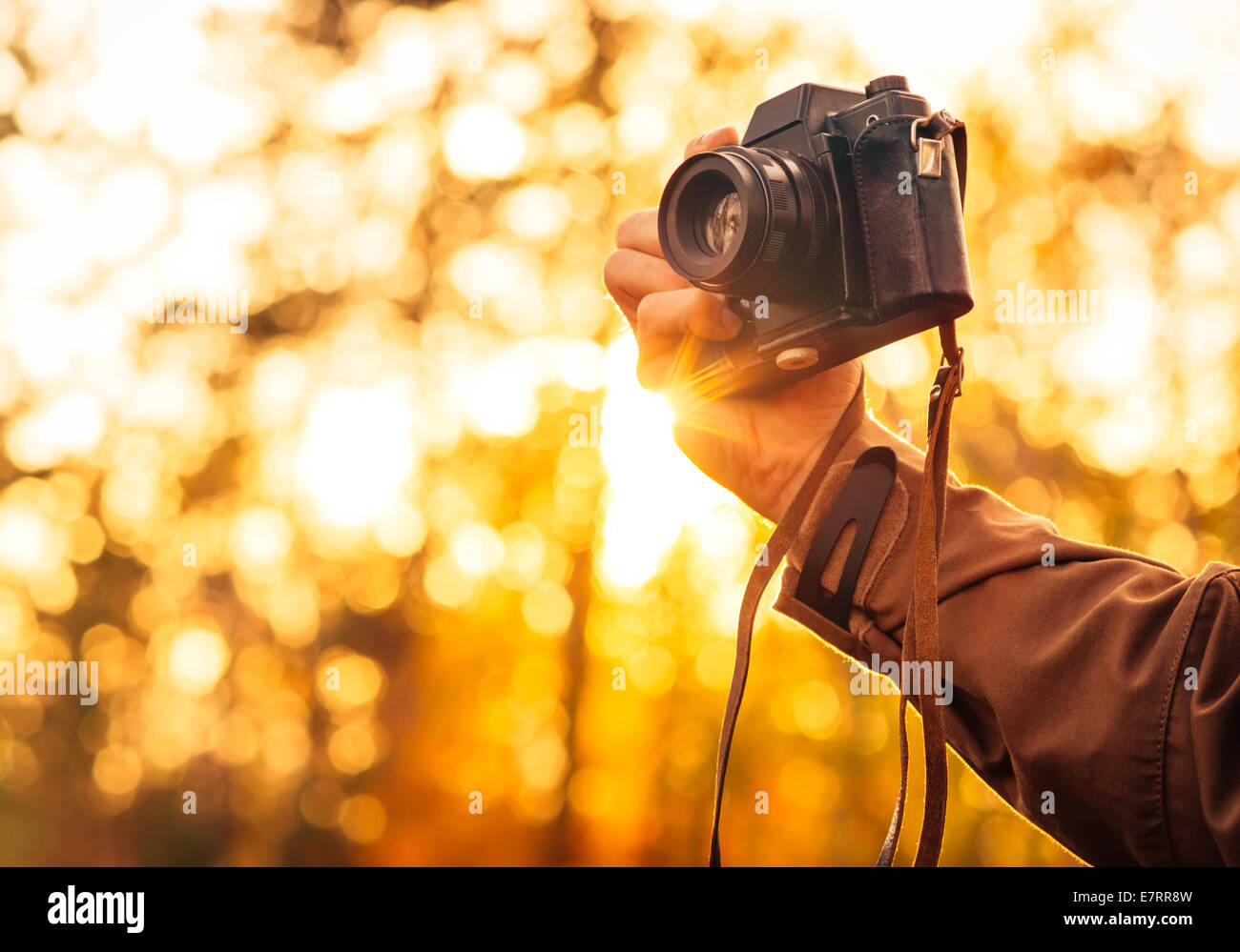 Man mano che tiene retrò fotocamera foto Outdoor Lifestyle concetto con sole illumina bokeh di fondo la natura in autunno su sfondo Foto Stock