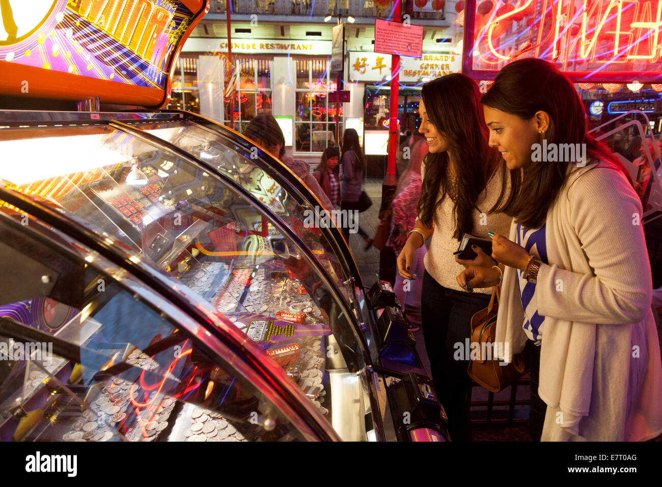 Due donne la riproduzione di giochi d'azzardo in un divertimento arcade, Soho, London REGNO UNITO Foto Stock
