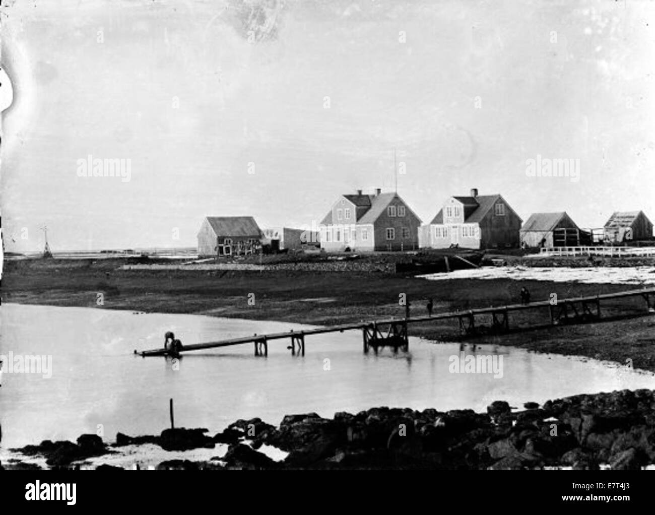 Questa foto cattura il porto e gli edifici commerciali di Akranes, Islanda, intorno al 1900. Mostra i negozi di legno e il porto affollato, riflettendo le attività economiche del tempo. Foto Stock