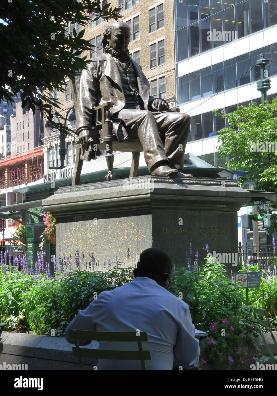Statua di Horace Greeley su un giorno di estate in Greeley Square, New York City. Tavoli e sedie circondano la statua. Foto Stock
