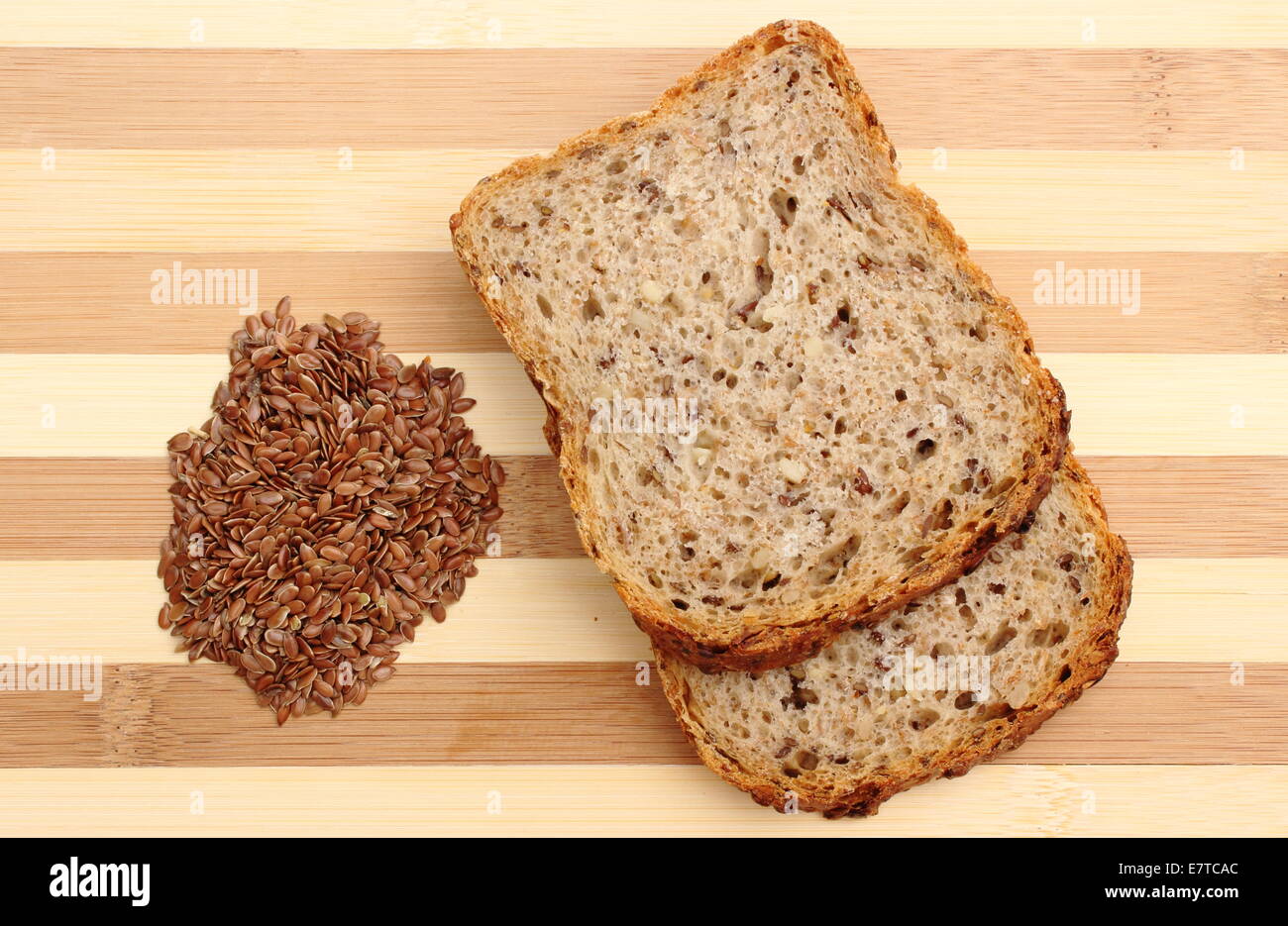 Semi di lino sul tagliere con fette di pane integrale Foto Stock