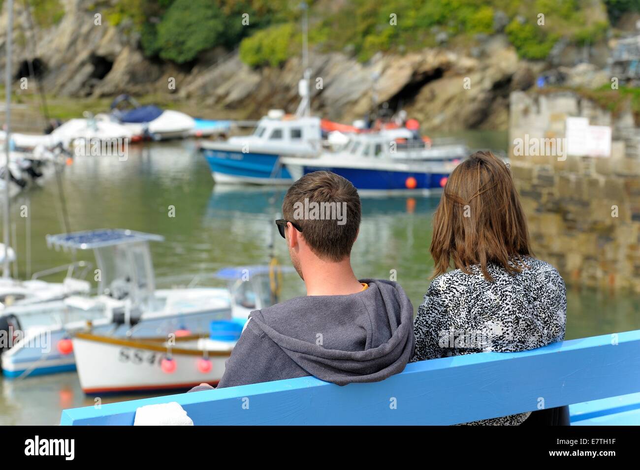 Una giovane coppia seduta su una panchina nel porto di Newquay Cornwall Inghilterra Regno Unito Foto Stock