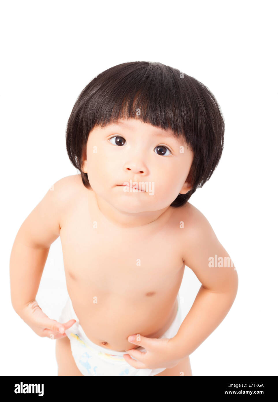 Carino Baby girl in un pannolino in piedi e guarda in alto isolato su sfondo bianco Foto Stock