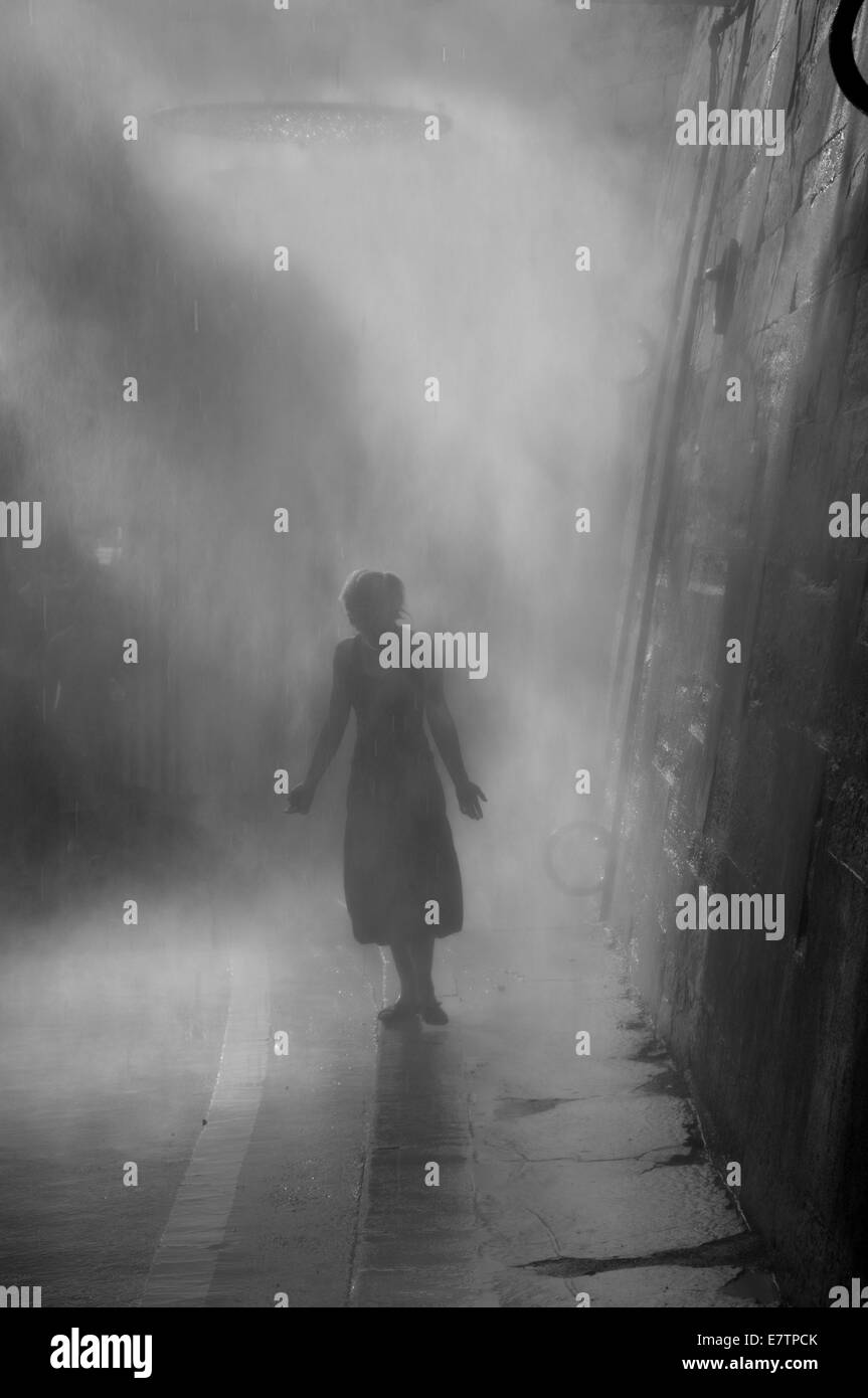 Donna in piedi su un marciapiede misty Foto Stock