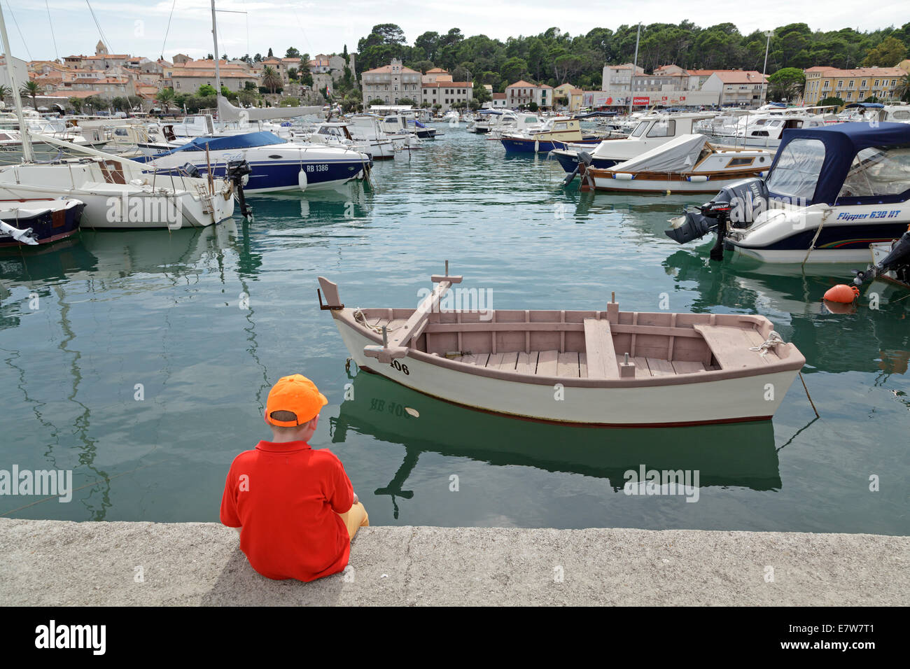 Ragazzo seduto sulla banchina a parete, porto, Città di Rab, isola di Rab, golfo di Kvarner, Croazia Foto Stock