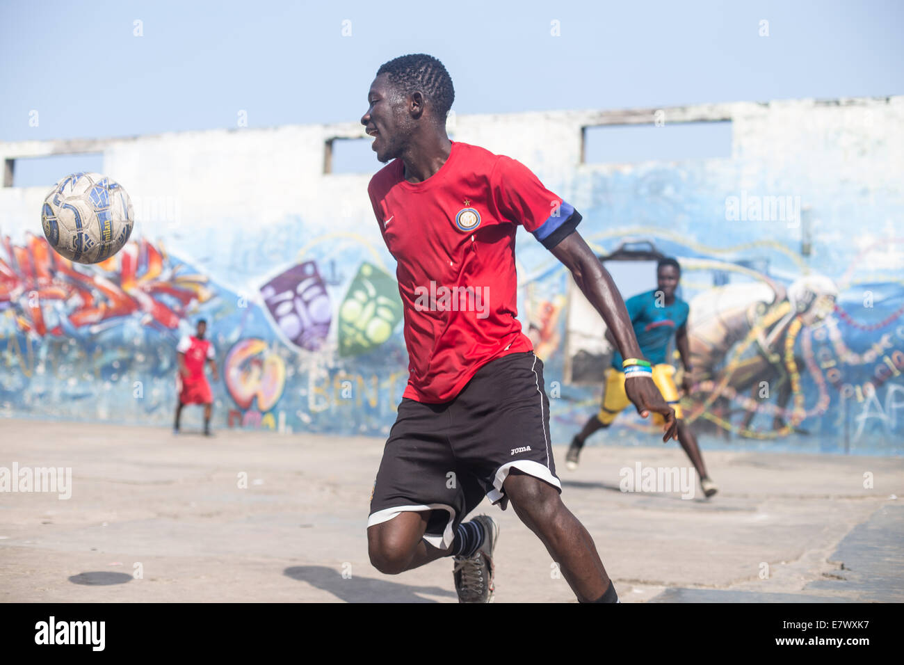 Ragazzi che giocano a calcio con graffiti in background in Accra in Ghana Foto Stock