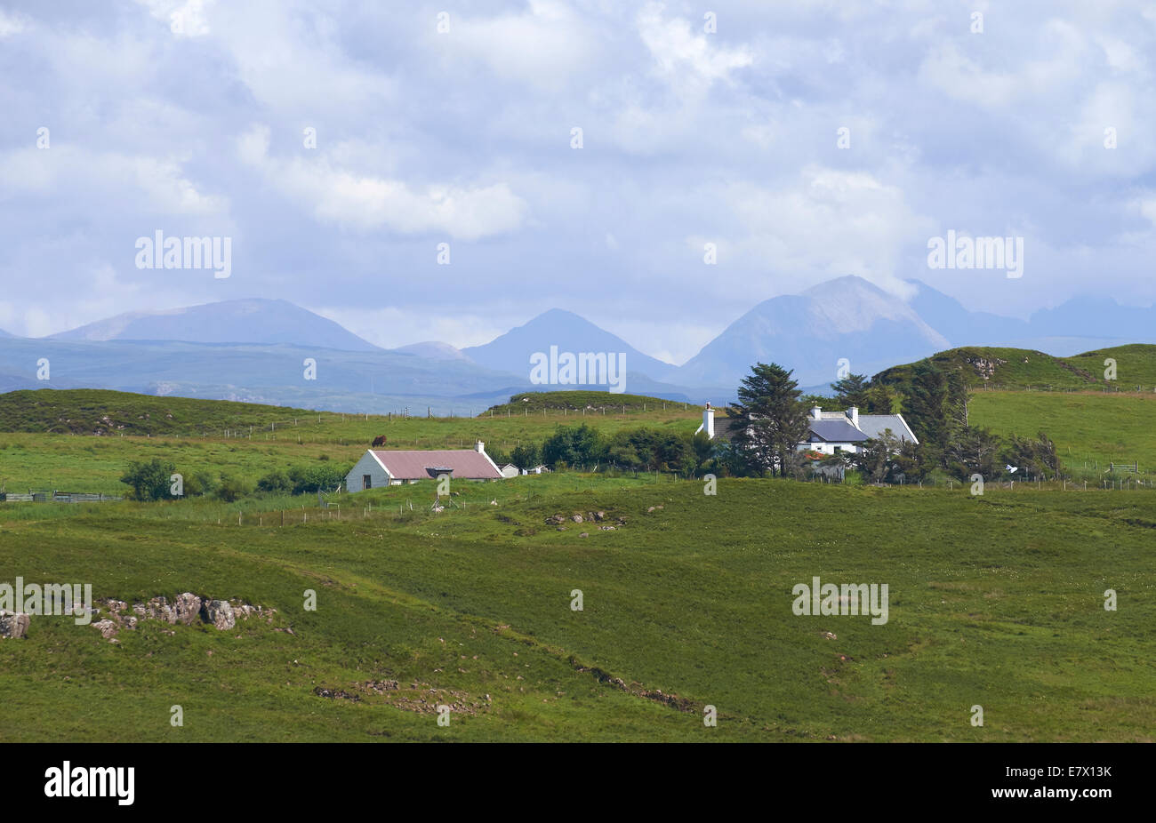 Un piccolo insediamento sull'Isola di Skye con il rosso e il nero Cuillins nella distanza. Foto Stock