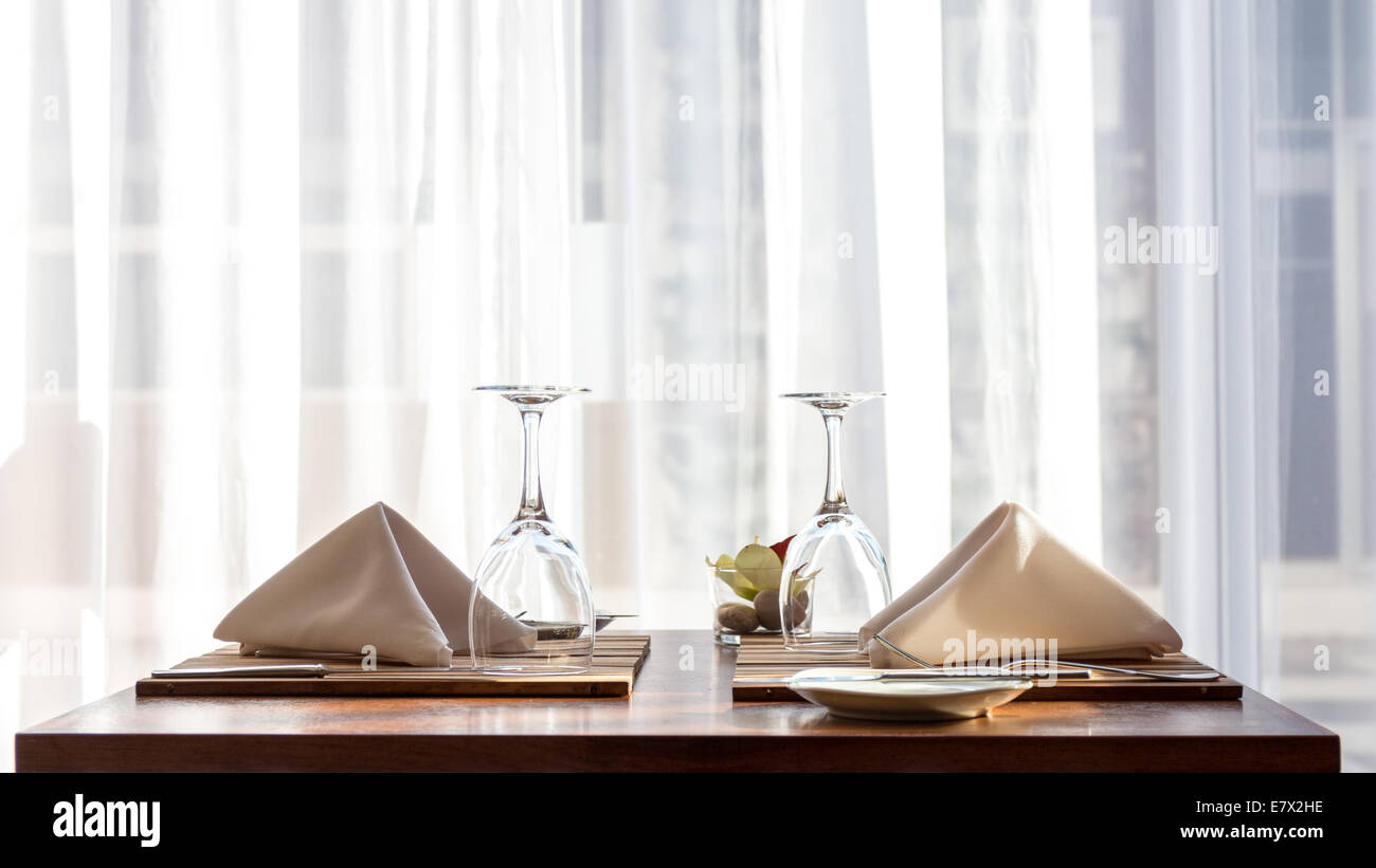 Un semplice e ben disposto un tavolo per due, con un panno di tovaglioli e bicchieri di vino Foto Stock