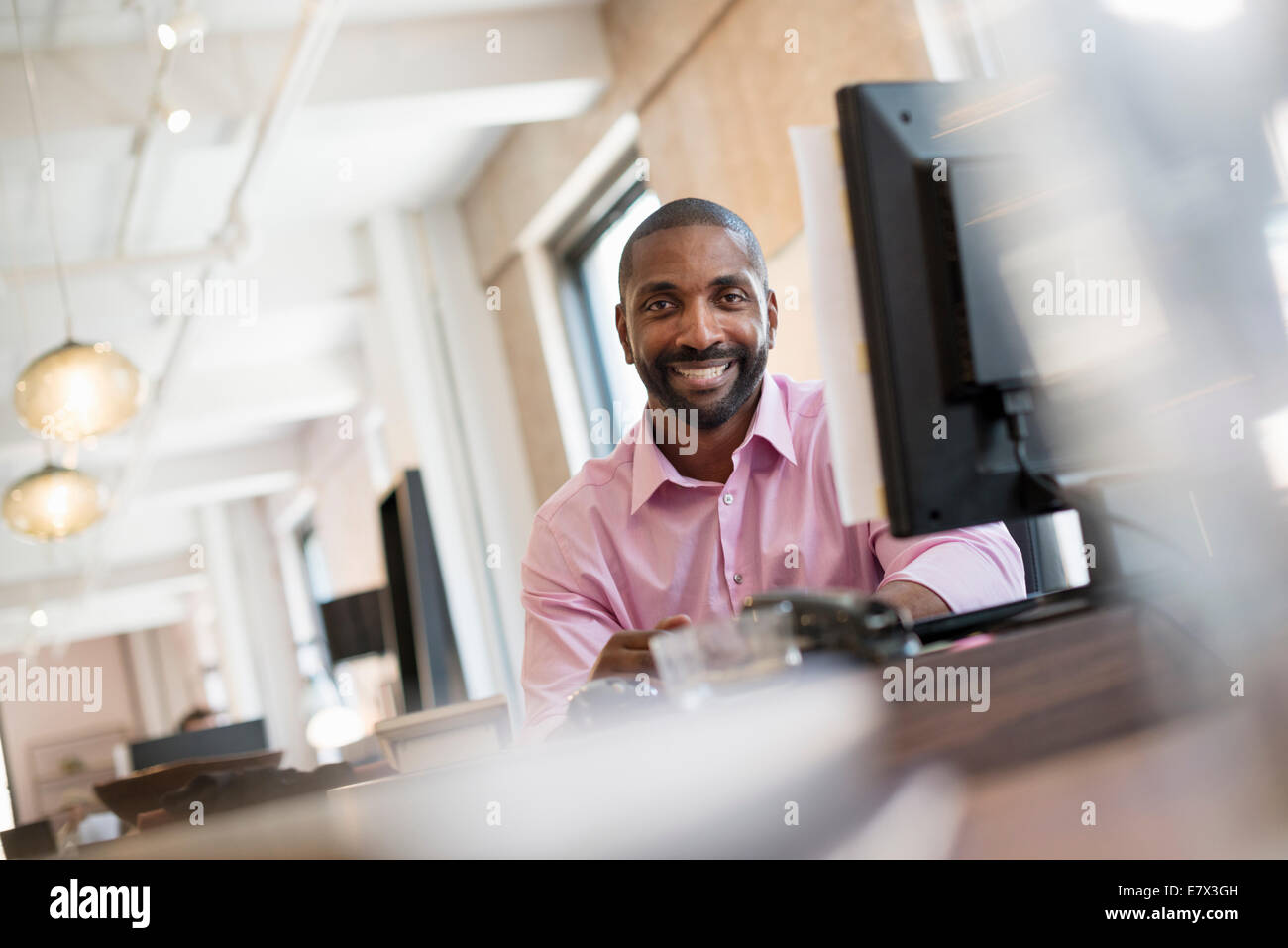 Vita in ufficio. Un uomo seduto alla scrivania di un monitor di un computer. Foto Stock