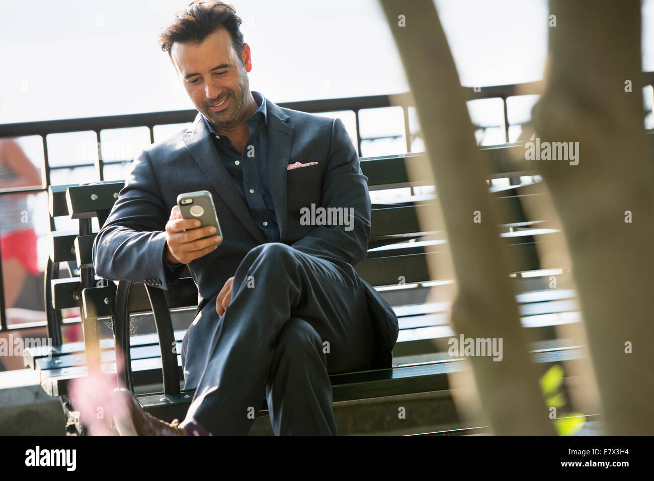 Un imprenditore seduto controllando il suo telefono, ridendo. Foto Stock