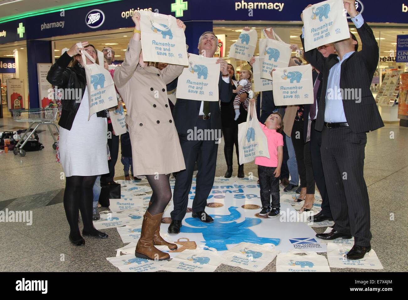 Edinurgh, Scozia. 25 Settembre, 2014. Richard Lochhead, armadio scozzese Segretario per gli affari rurali, il cibo e l'ambiente (3 L), mostra riciclabile borse di stoffa con il pubblico in un centro commerciale di Edimburgo, in Scozia, a sett. 25, 2014. Il governo scozzese di giovedì ha lanciato un sette settimane di campagna di sensibilizzazione del pubblico sul singolo utilizzare sacchetti di carica per proteggere l'ambiente naturale. Da ott. 20, tutti i dettaglianti in Scozia si riserva di addebitare una tassa obbligatoria di almeno 5 pence (circa 0.084 dollari USA) per ciascun nuovo vettore borsa danno agli acquirenti, se esso è fatto di plastica © Xin Foto Stock