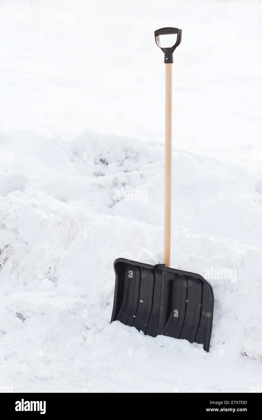 Snowshowel nere con manico di legno nel cumulo di neve Foto Stock