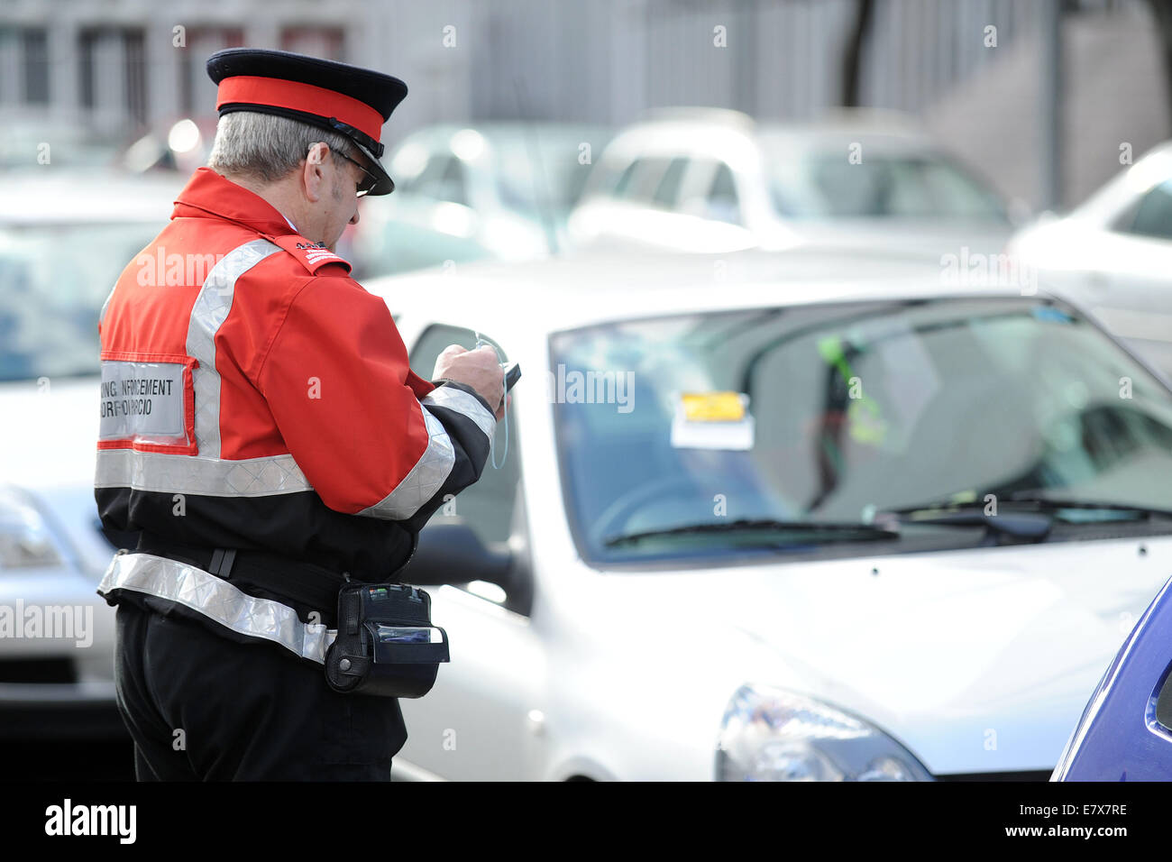 Un vigile (civile esecuzione officer) di pattuglia emettere i biglietti per il parcheggio per le auto parcheggiate in sosta a Cardiff, nel Galles. Foto Stock