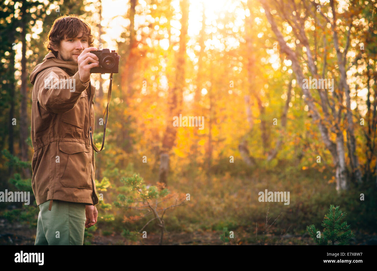 Giovane uomo con retro fotocamera uno stile di vita all'aperto alla luce del sole natura foresta sullo sfondo Foto Stock