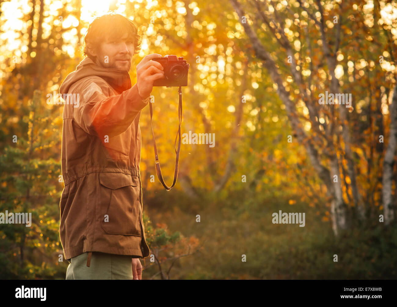 Giovane uomo con retro fotocamera uno stile di vita all'aperto alla luce del sole natura foresta sullo sfondo Foto Stock