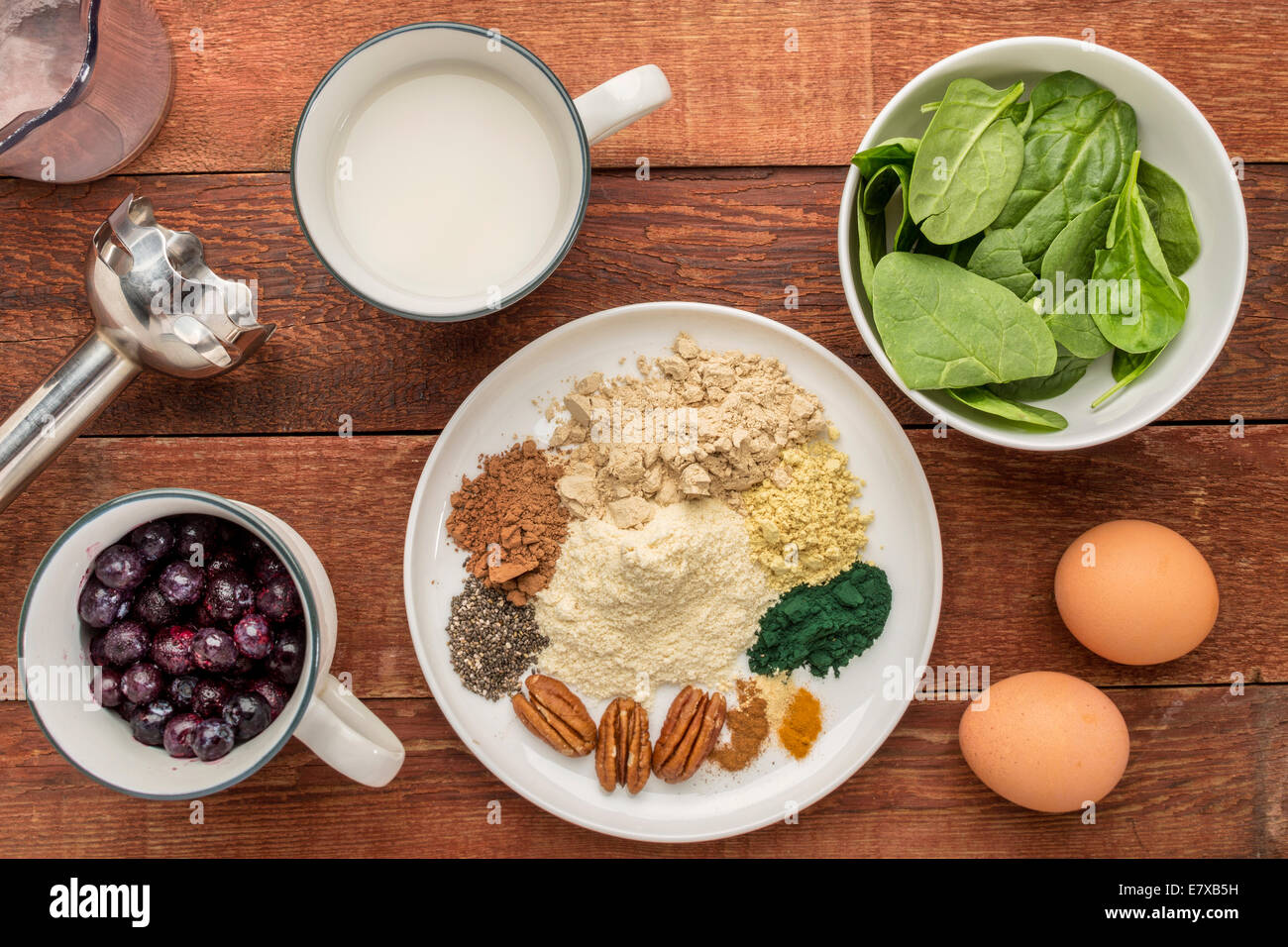 Gli ingredienti di una sana prima colazione: frullato di latte di mandorla, uova crude, spinaci freschi, mirtilli surgelati, proteina di siero di latte Foto Stock