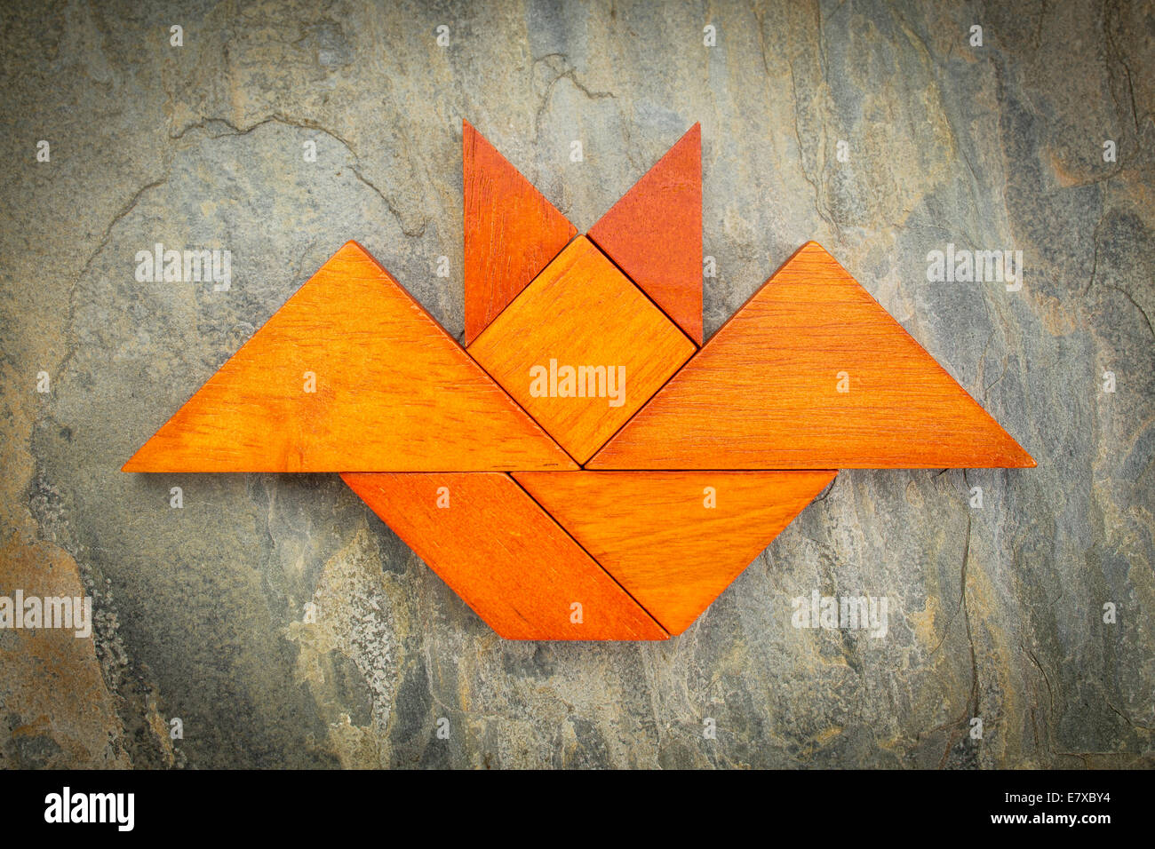 Immagine astratta di un flying bat costruito da sette tangram pezzi di legno su una roccia di ardesia sfondo, concetto di Halloween Foto Stock