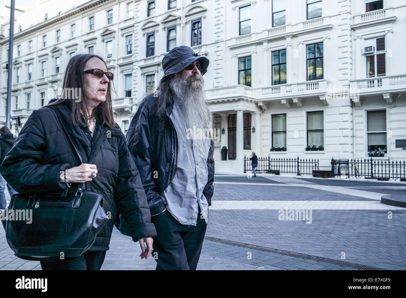 L'uomo con una lunga barba bianca e la donna a piedi giù per una strada di Londra Foto Stock