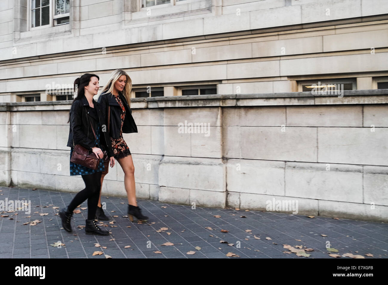 Due giovani ragazze a piedi lungo una strada di Londra, street photography. Foto Stock