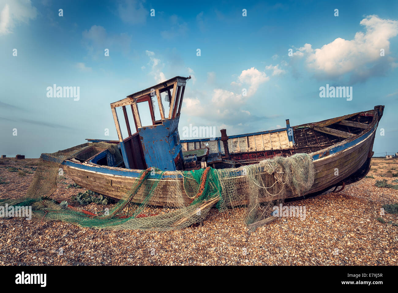 Vecchio di legno barca da pesca lavato fino a una spiaggia di ciottoli Foto Stock