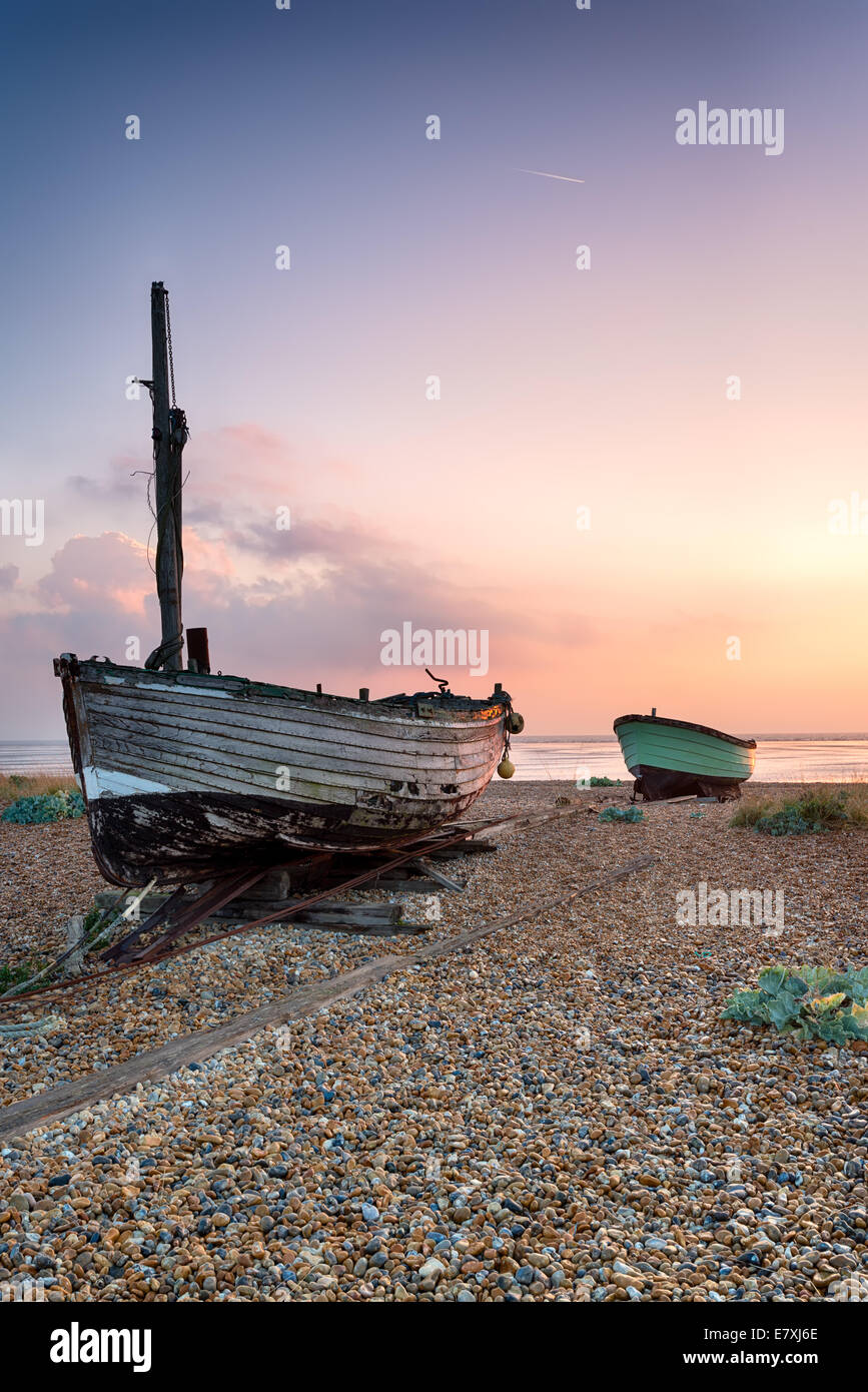 Bellissima alba su vecchie barche di legno su una spiaggia di ciottoli in Lydd, Kent Foto Stock