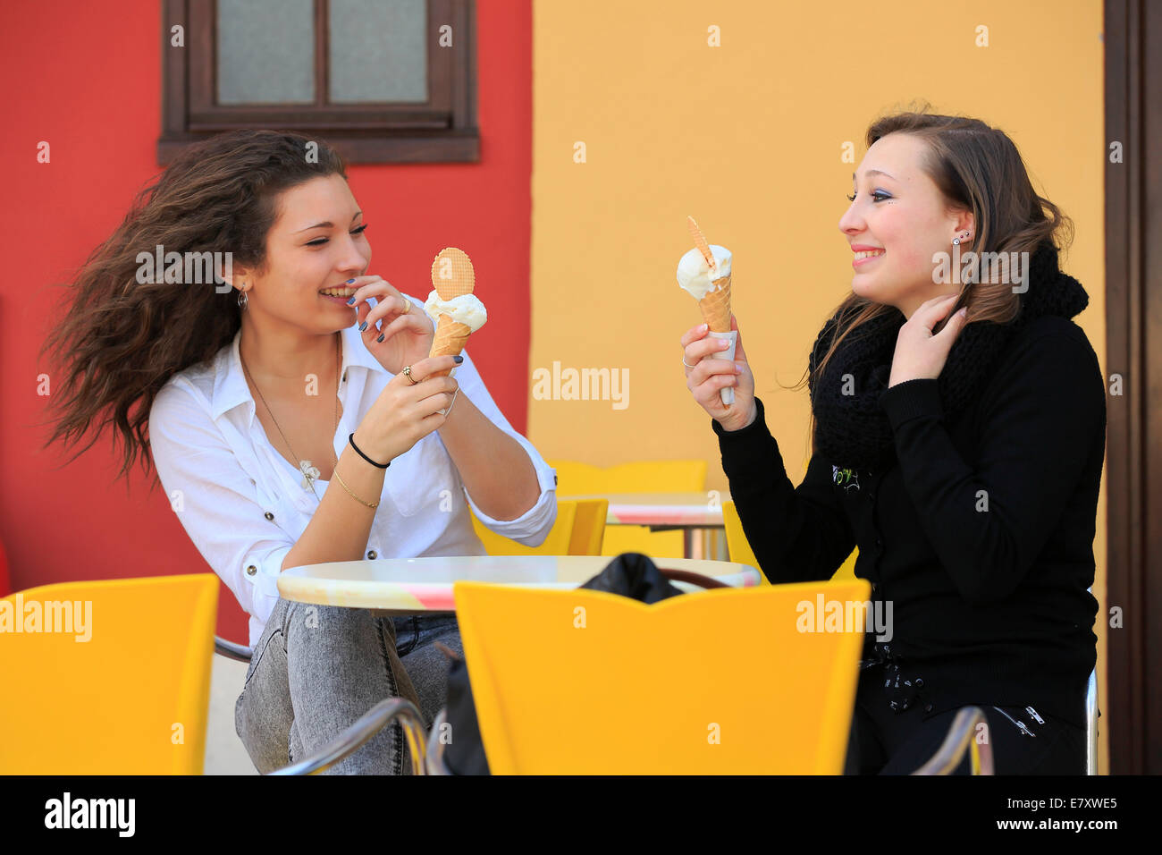 Due amiche, adolescenti, mangiare il gelato dal cono sulla terrazza di una gelateria, Menton, Alpi Marittime Foto Stock