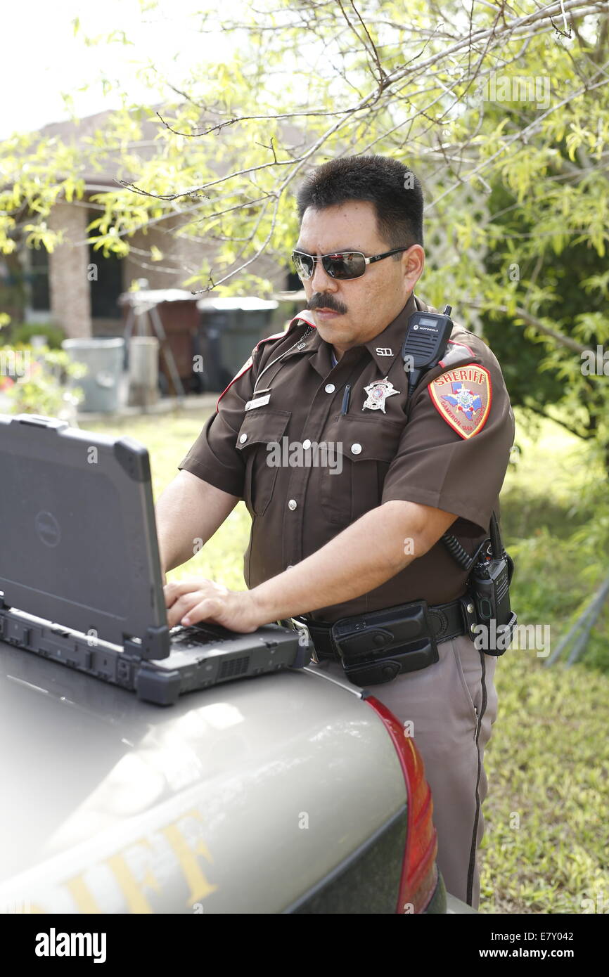 Brownsville, TX USA 25SEP14: Vice Sheriff Jorge Marquez finisce la relazione di un incidente stradale con un computer portatile Foto Stock