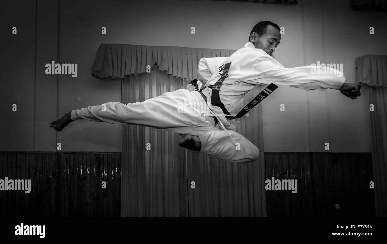 Un giovane uomo di mettere in pratica i suoi Taekwondo kick Foto Stock