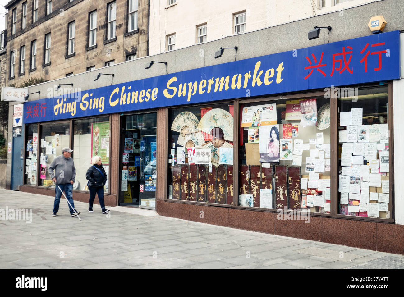 Due persone camminare davanti a un supermercato cinese su Leith Walk, Edimburgo Foto Stock