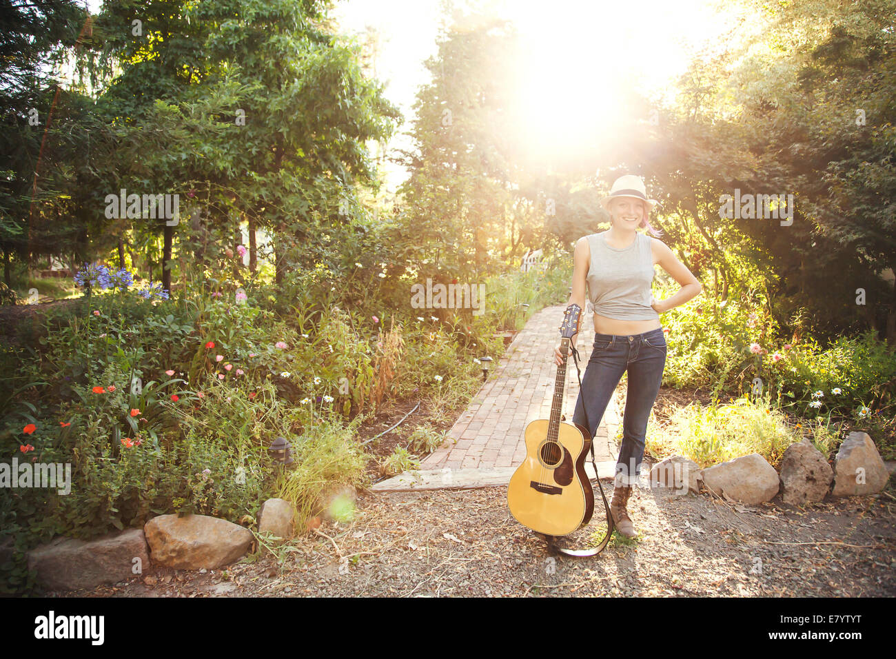 Giovane donna con la chitarra acustica in giardino Foto Stock