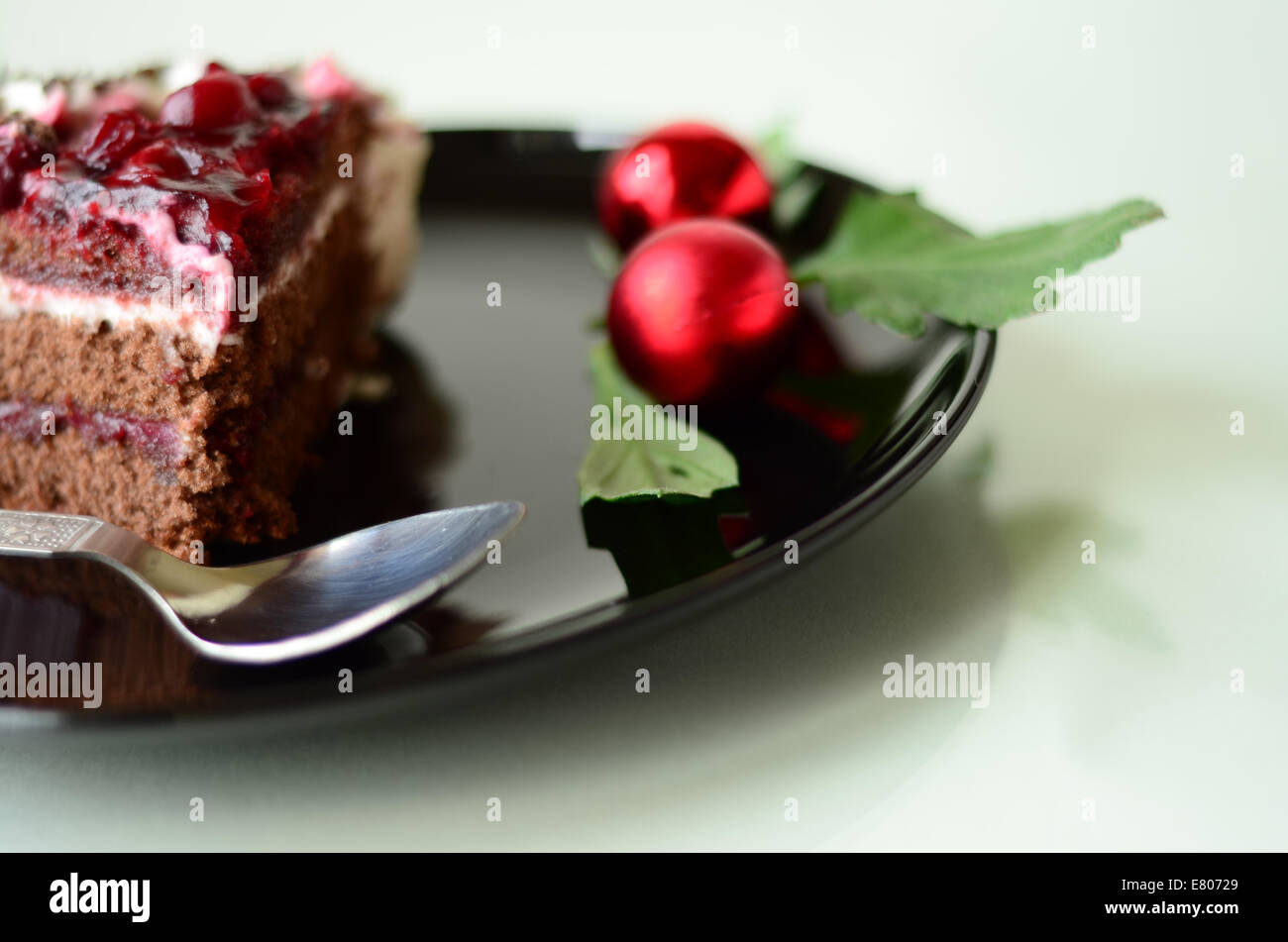 Torta della Foresta Nera del pezzo in una piastra nera con decorazione di Natale e un cucchiaio Foto Stock