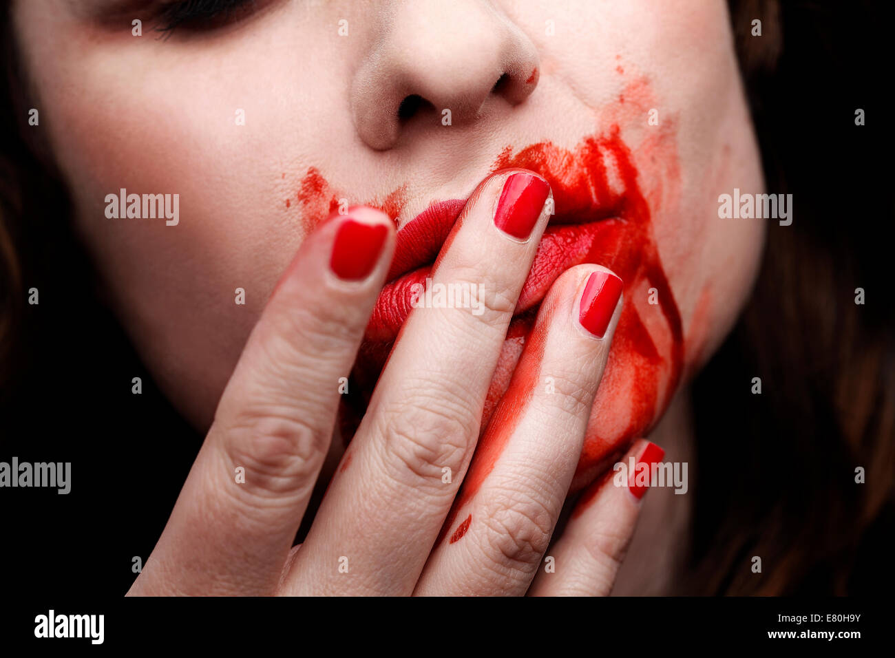 Vampiro femmina leccare il sangue fuori della sua dita Foto Stock