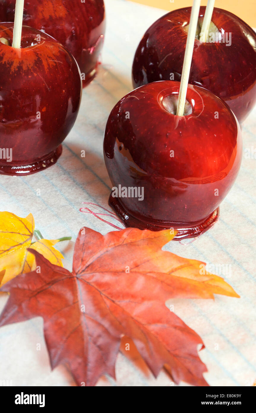 Rendendo red toffee mele per Halloween dolcetto o scherzetto cibo candy, sulla carta da forno e cottura rack con Autumn Fall leaf Foto Stock