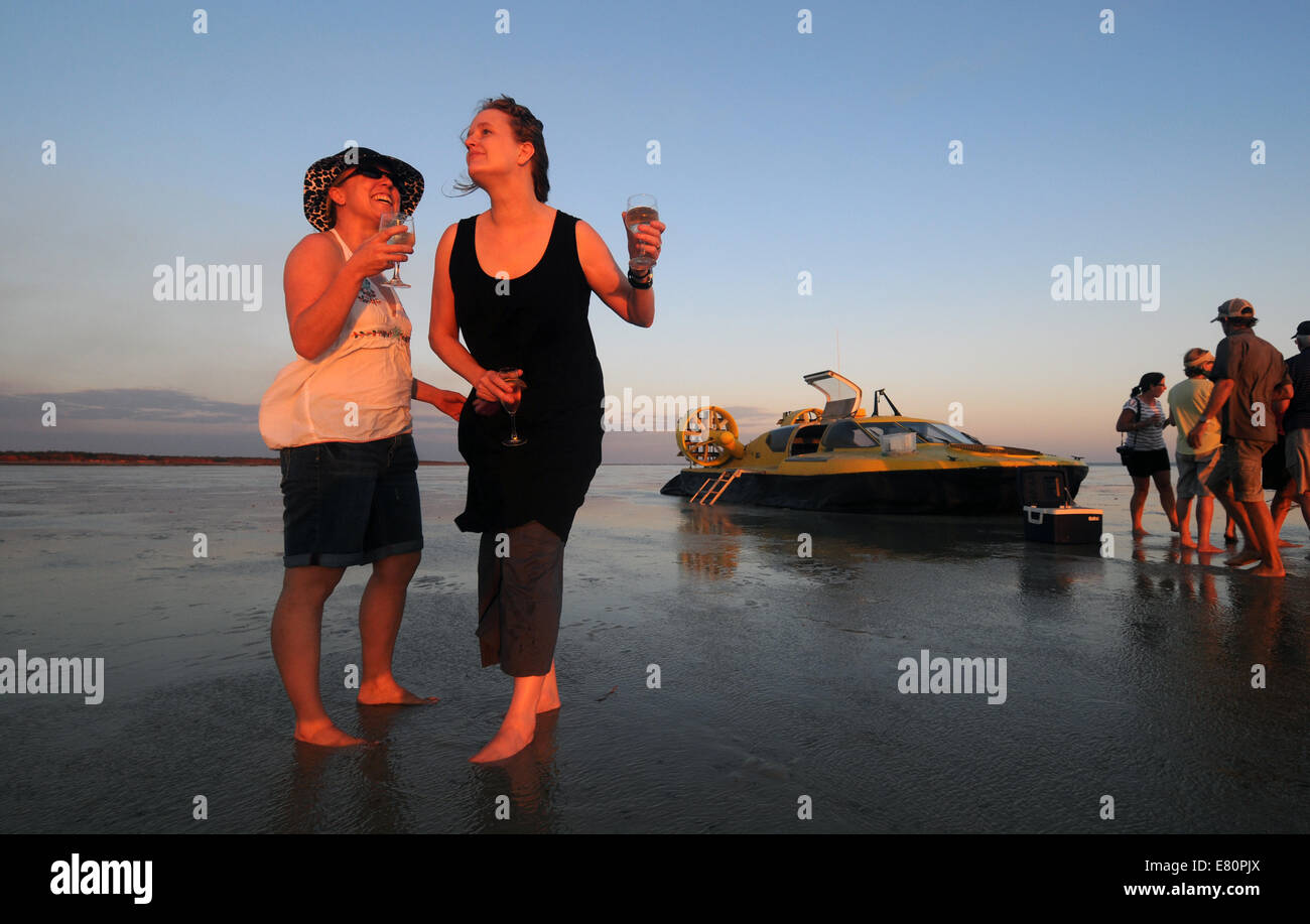 I turisti avente un drink al tramonto sulla bassa marea sandflats durante il tour di hovercraft in Roebuck Bay, Broome, Kimberley, Australia occidentale Foto Stock