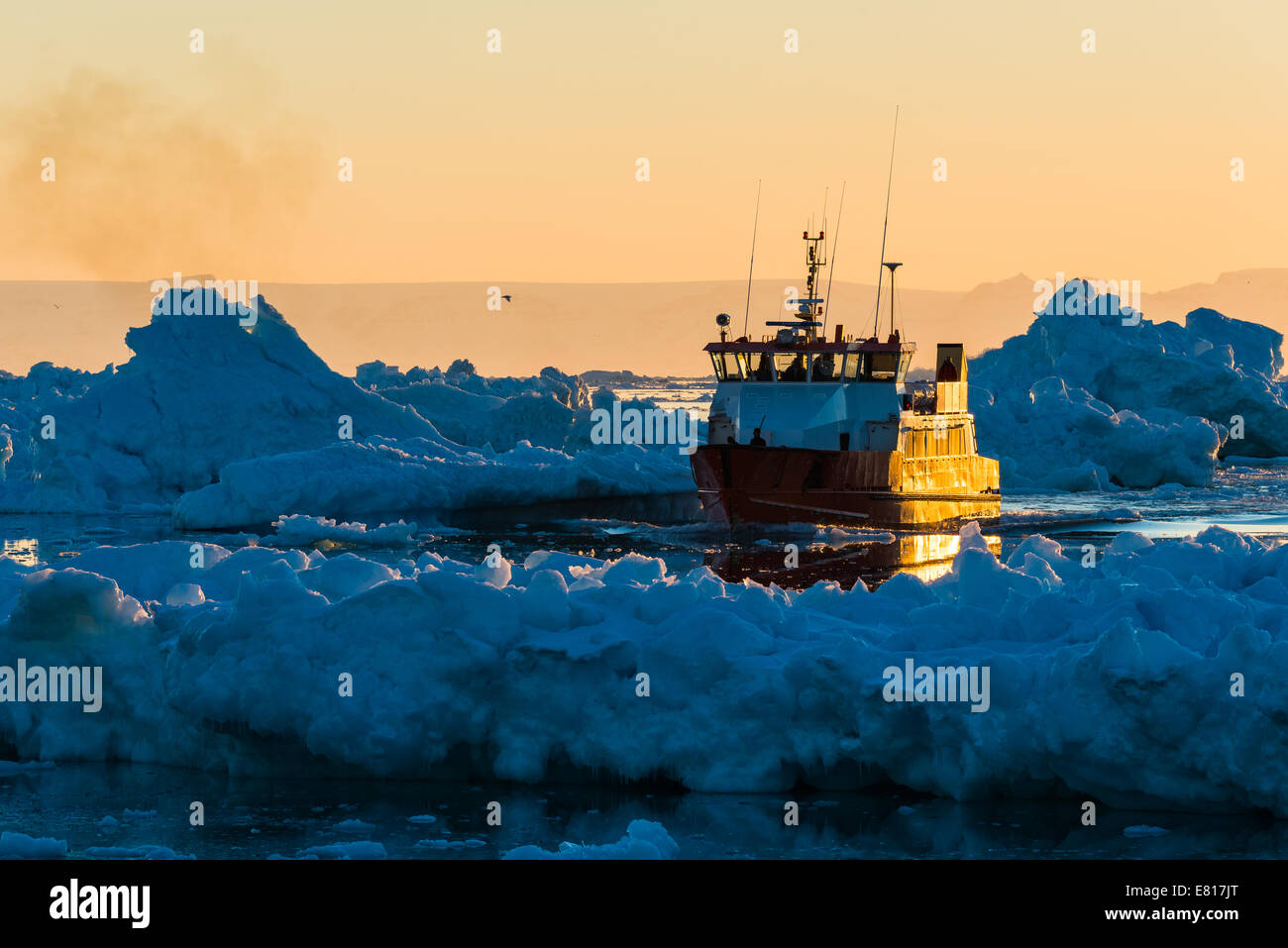 Barca da pesca naviga glacier-riempita acque al tramonto Foto Stock